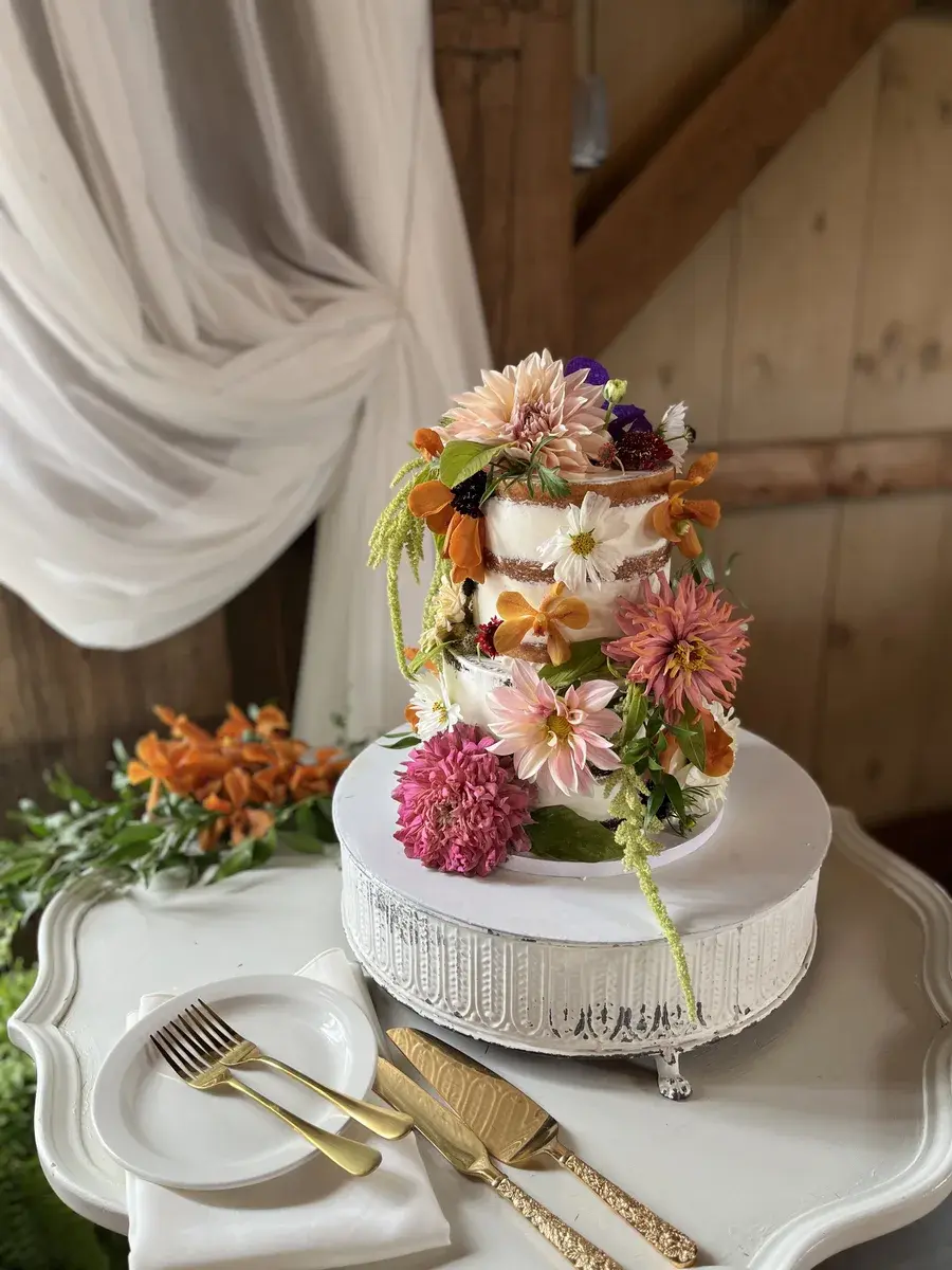 A tiered wedding cake covered in fresh dahlias and orange blooms
